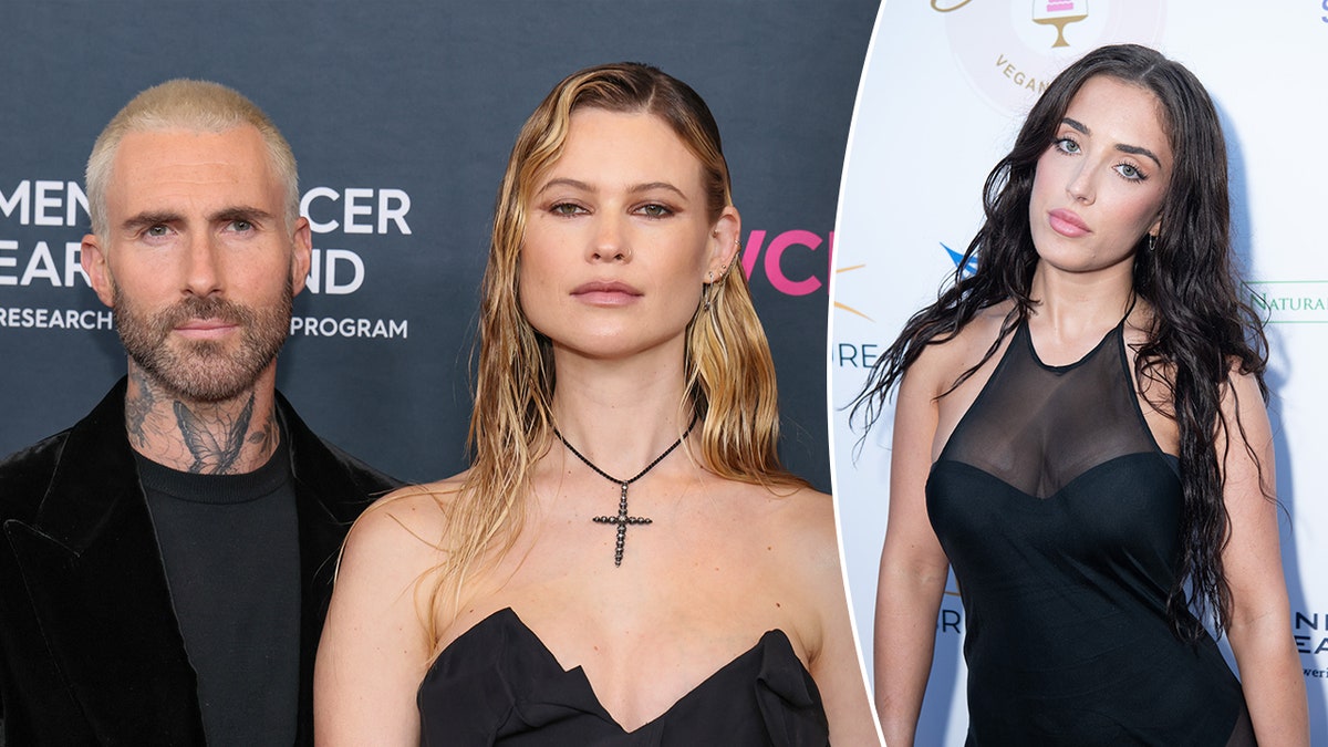 Adam Levine in a black jacket stands next to Behati Prinsloo in a black dress and cross necklace split Sumner Stroh in a black dress on the carpet