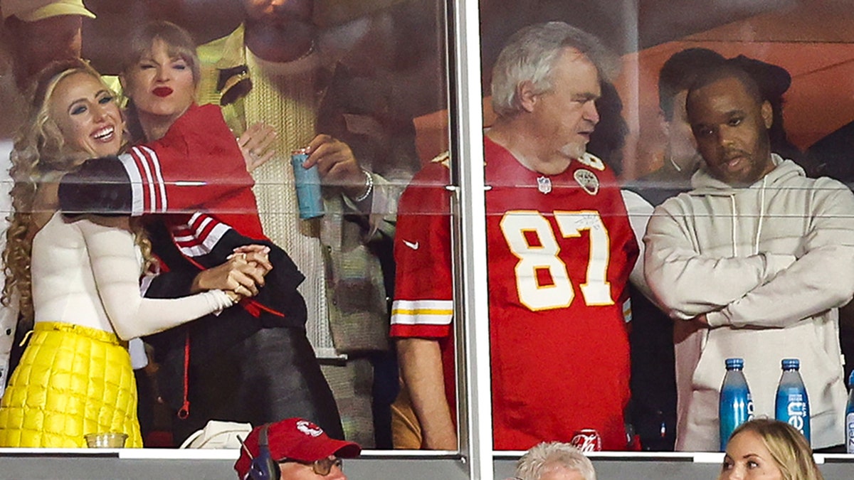Taylor Swift hugs Brittany Mahomes as Ed Kelce talks to someone in the suite watching the Chiefs game