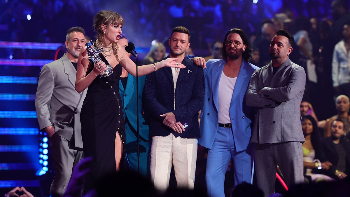 woman speaking on stage with men behind