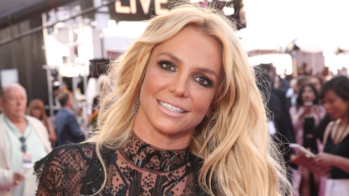 Britney Spears usa vestido preto transparente no tapete vermelho 