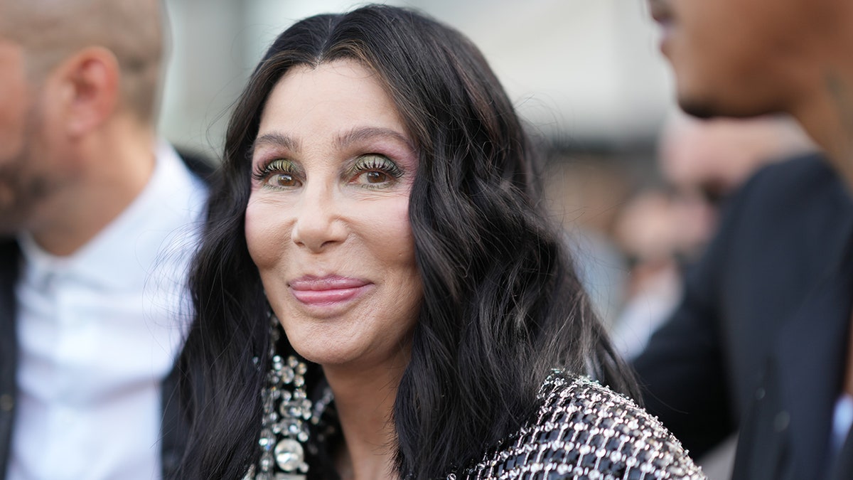 Cher soft smiles in a plaid coat in Paris, France