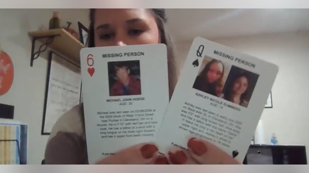 Devin Althen, a law enforcement liaison with the nonprofit Cleveland missing, holds up two cards.