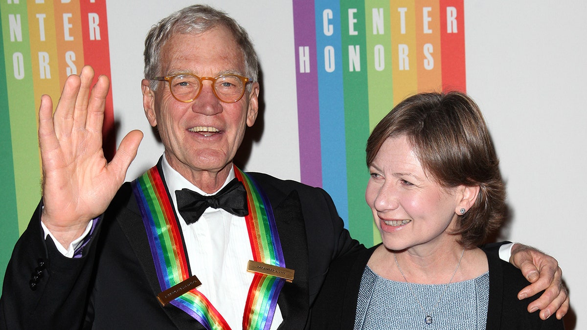 David Letterman in a tuxedo and rainbow ribbon around his next smiles with wife Regina at the Kennedy Center Honors