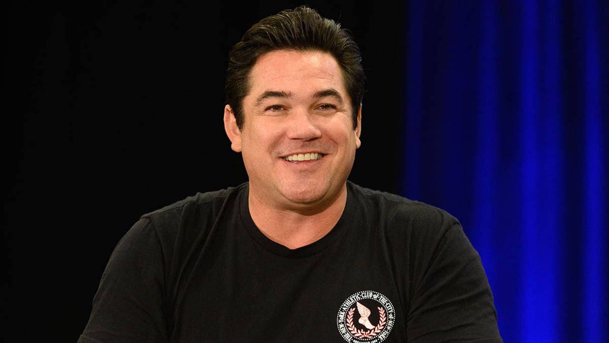 Dean Cain smiles for a photo in a black t-shirt