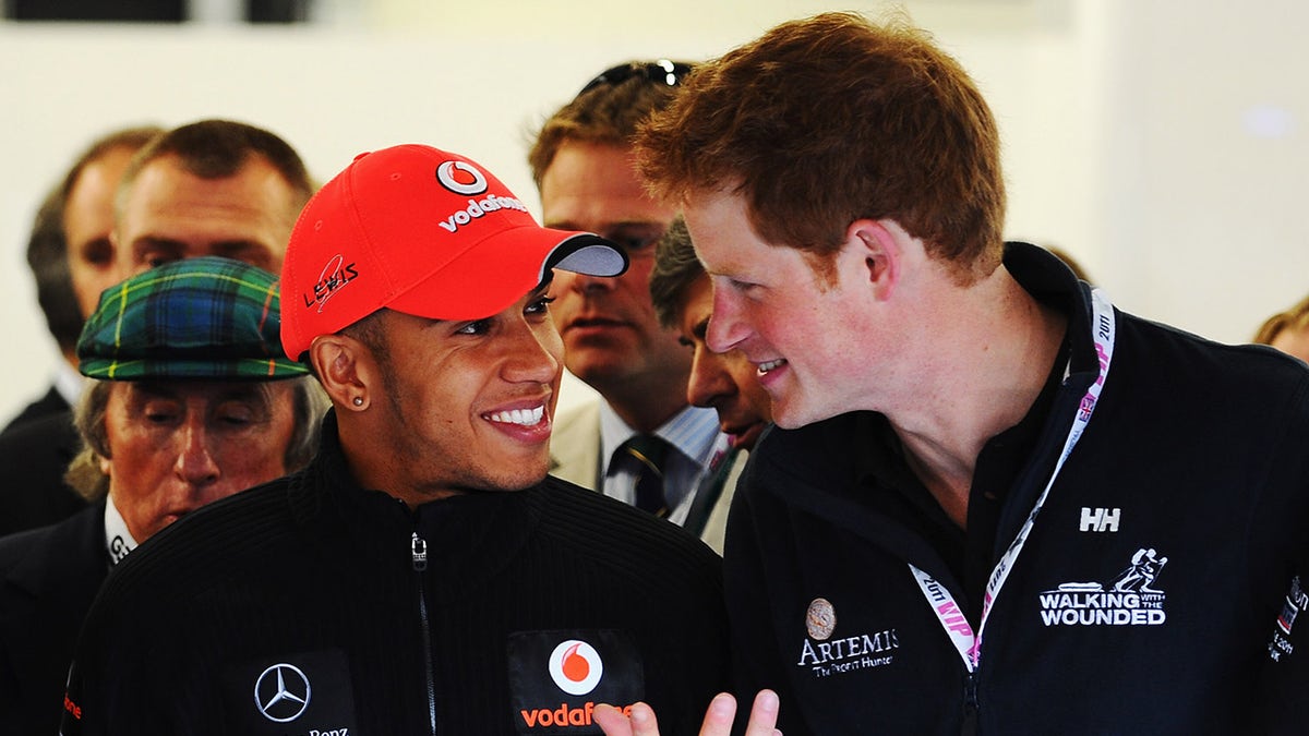 Lewis Hamilton smiles during animated chat with Prince Harry.