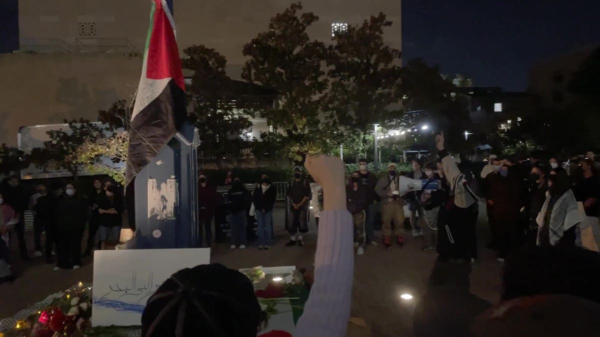 College students gathered at a vigil with their hands in the air