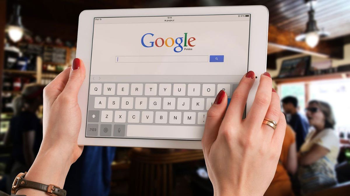 hands hold tablet with Google open