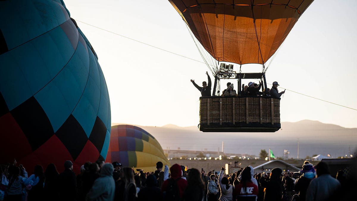 A balloon pilot waves to the crowd as he takes off during the Albuquerque International Balloon Fiesta on Oct. 7, 2023.