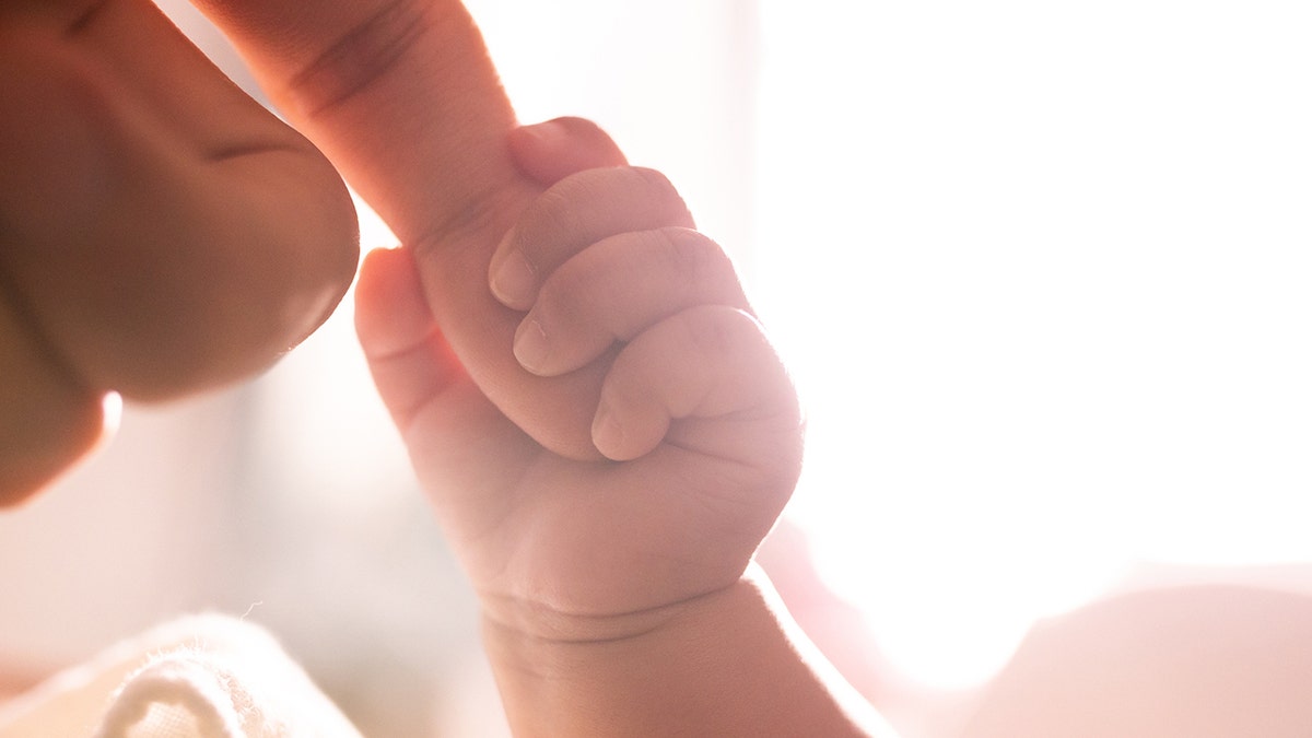 baby holding mother's finger