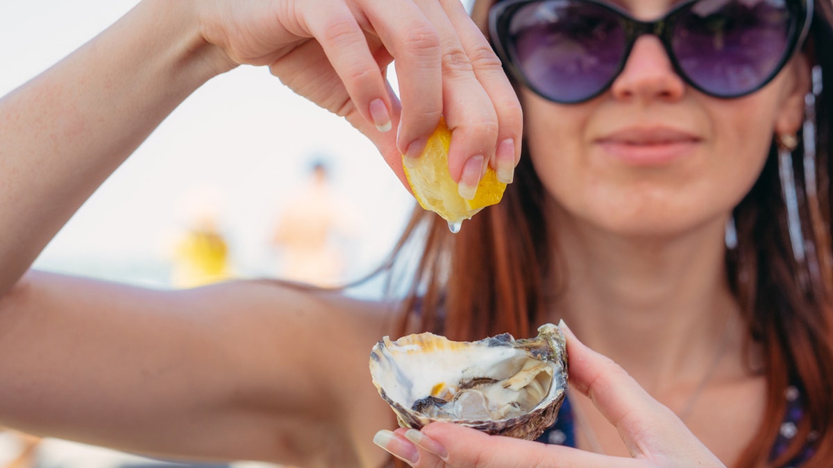 woman puts lemon on oyster