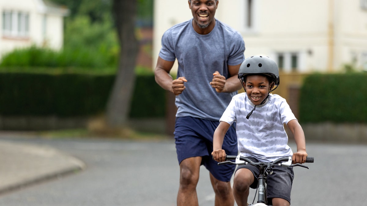 dad teaches son to ride bike