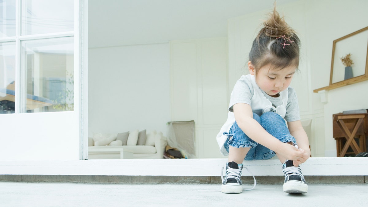 kid ties her own shoes