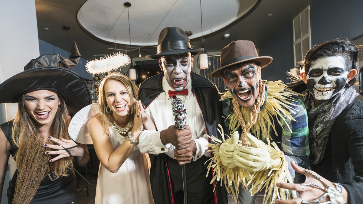ghostface horror movie Adults at a Halloween party wear costumes while celebrating.