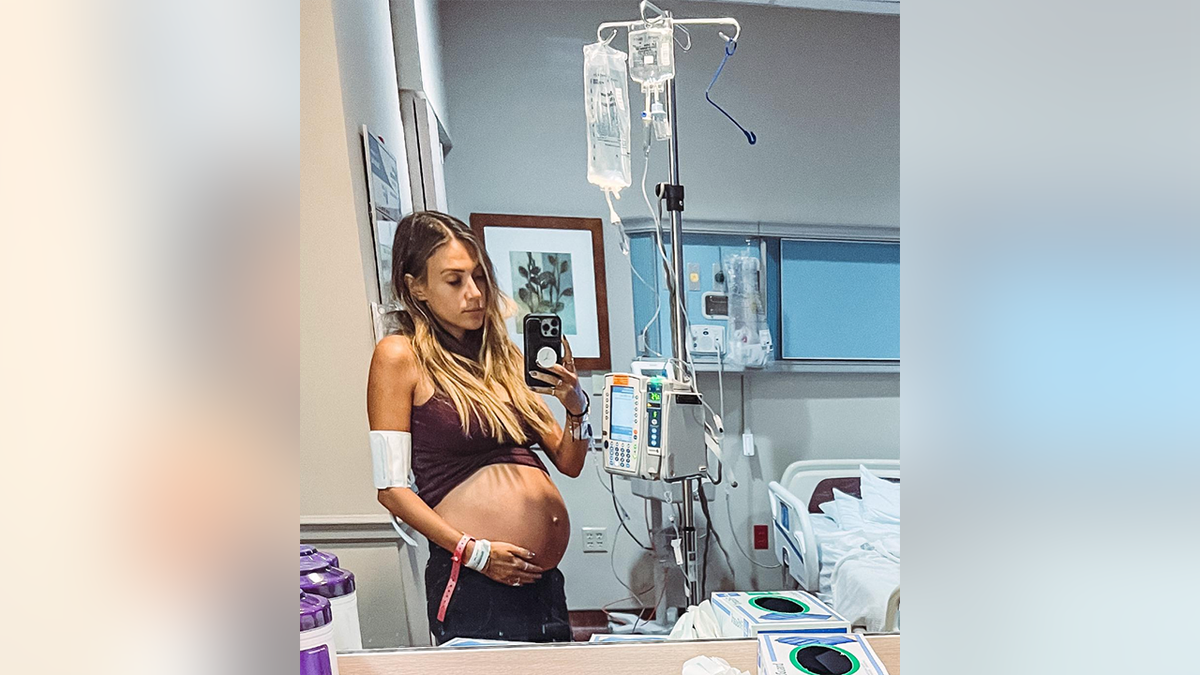 Jana Kramer cradling her stomach connected to an IV in the hospital