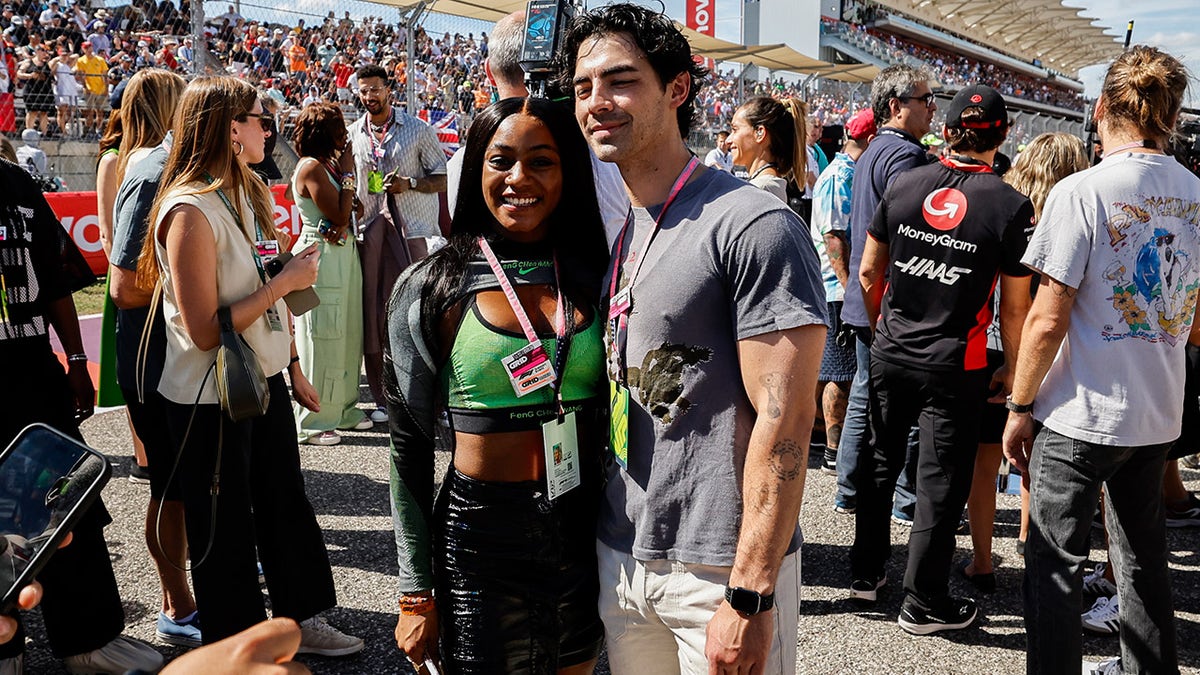 Joe Jonas and Sha'Carri Richardson smile at Formula One event.