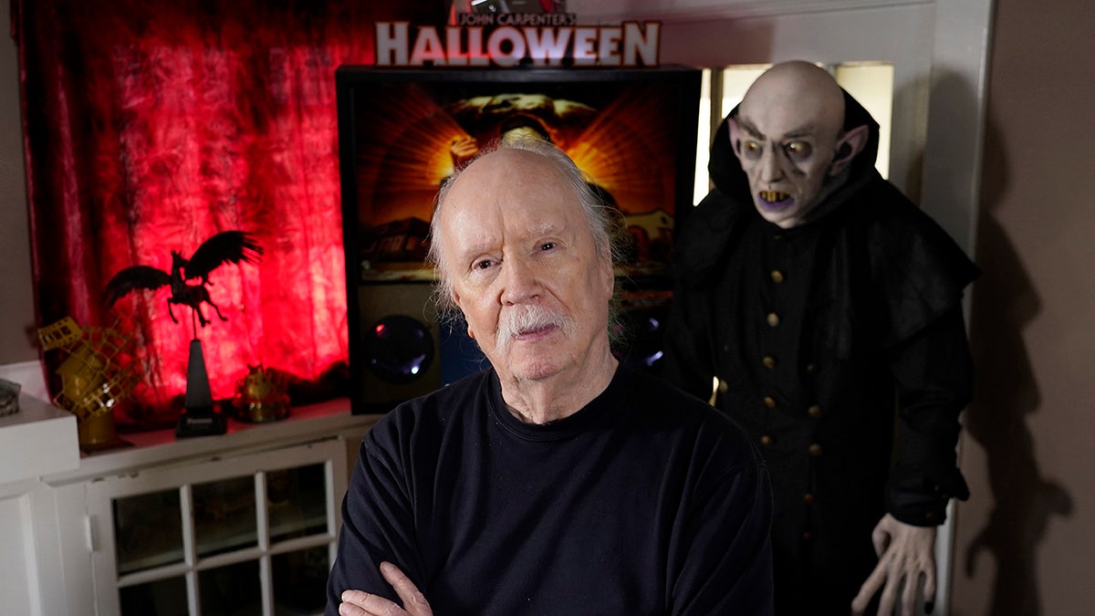 John Carpenter standing into from of a "Halloween" poster