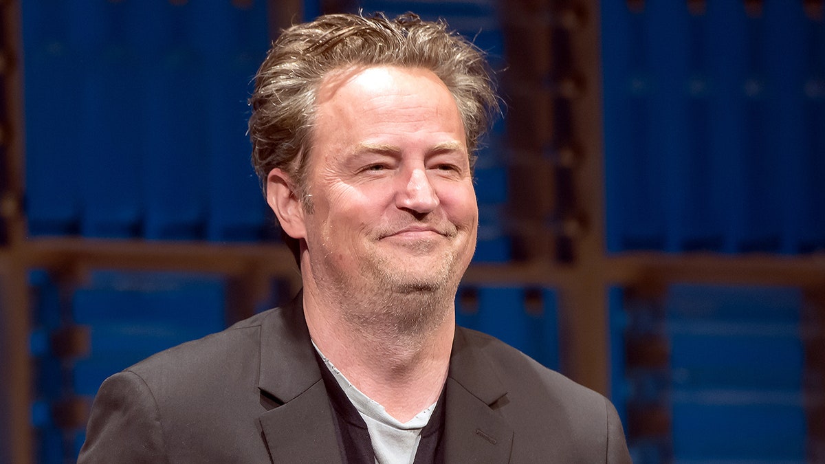 Matthew Perry sorride dolcemente in un blazer marrone a New York City