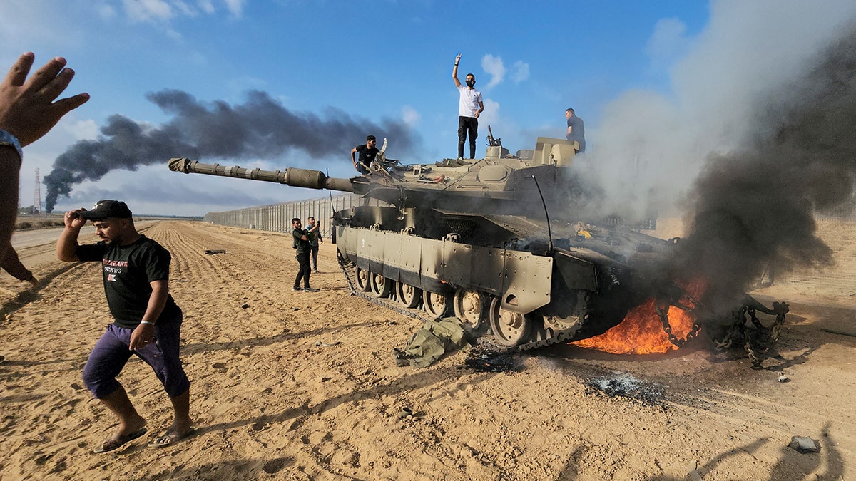 Palestinians celebrate a destroyed Israeli tank