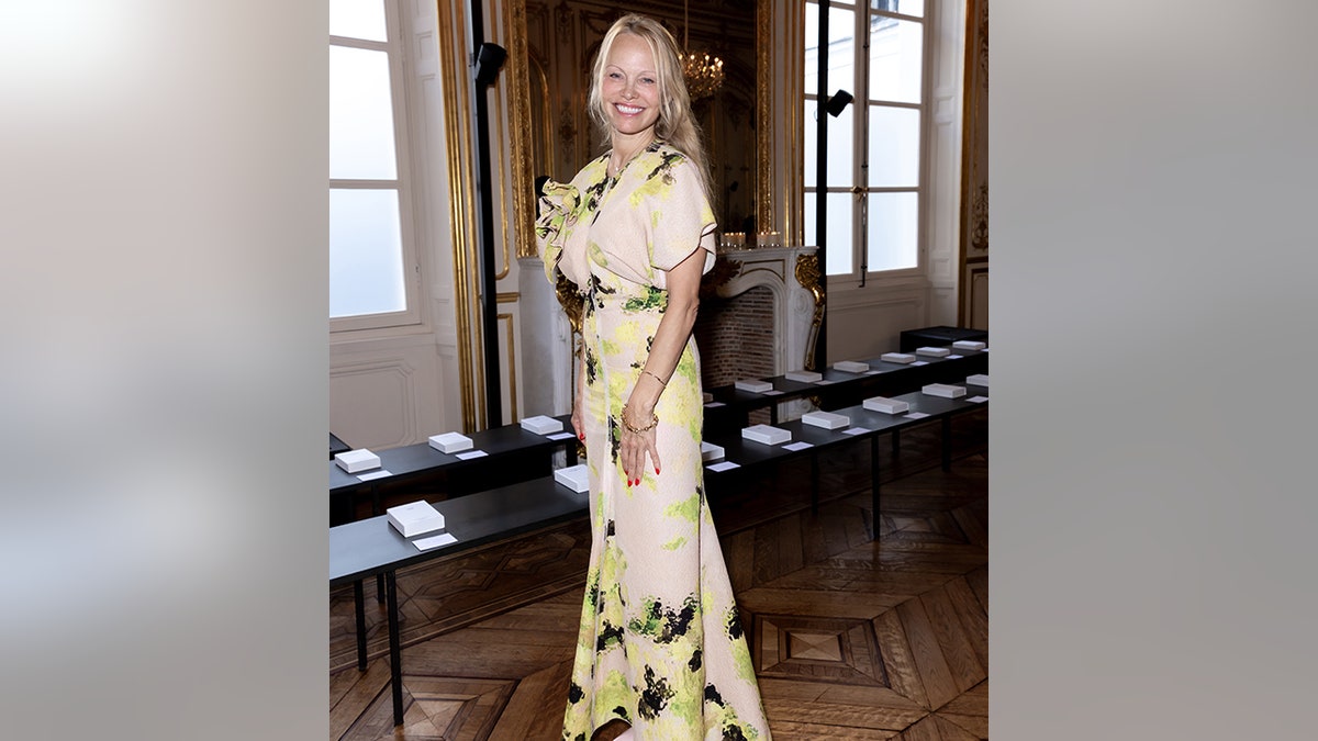 Pamela Anderson in a cream outfit at the Victoria Beckham fashion show in Paris