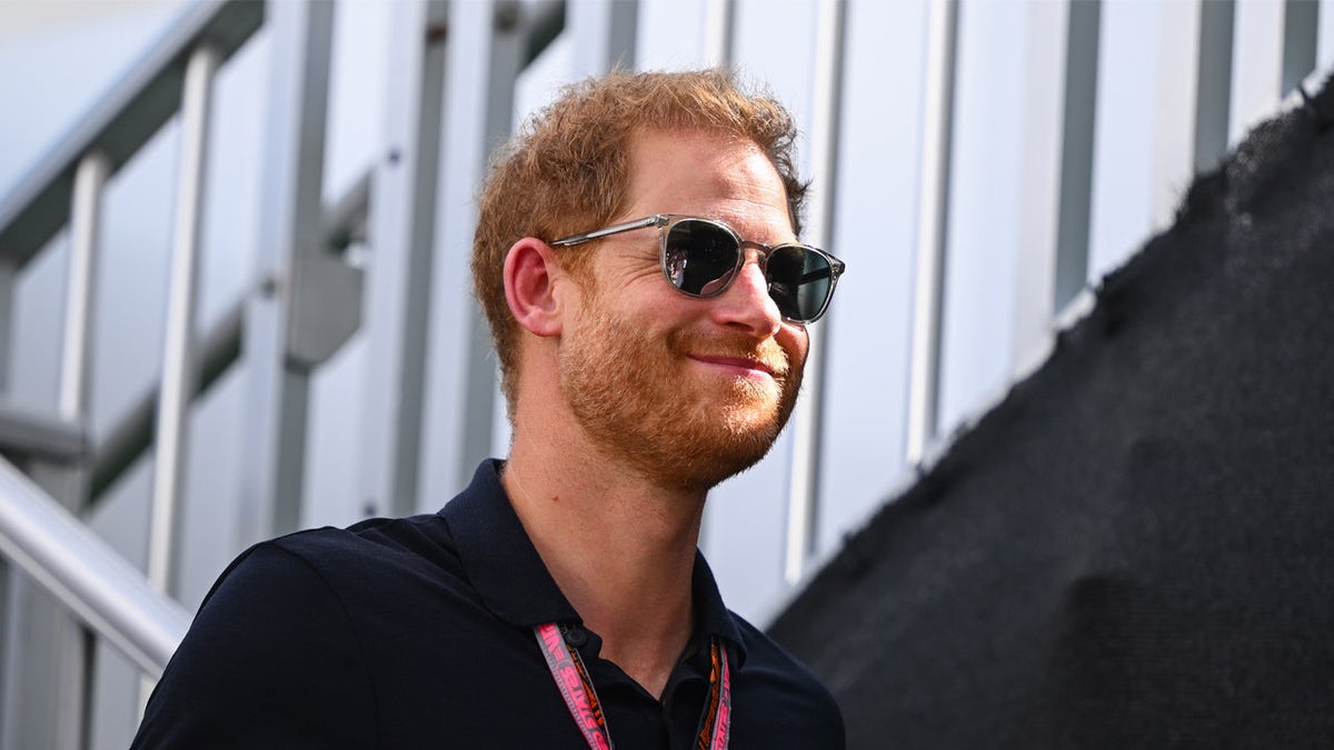 Prince Harry smiles while wearing sunglasses at F1 race