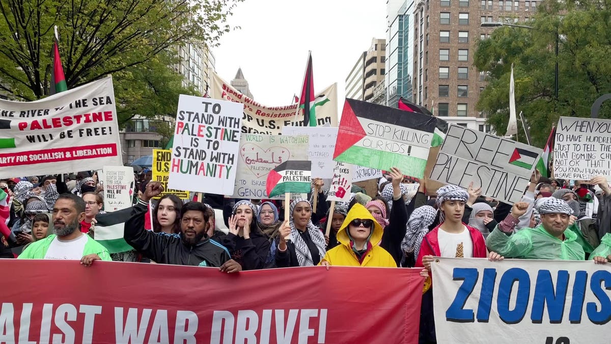 Manifestantes pró-Palestina seguram uma faixa enquanto marcham