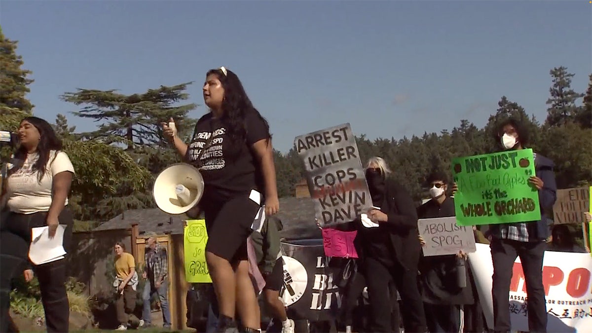 Protesters march through Seattle neighborhood holding signs, megaphone