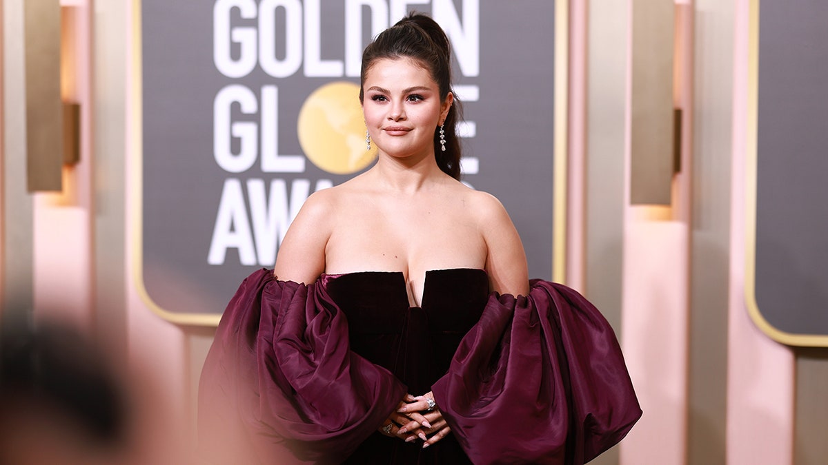 Selena Gomez in a black gown with a little V and massive poofy purple sleeves at the Golden Globes