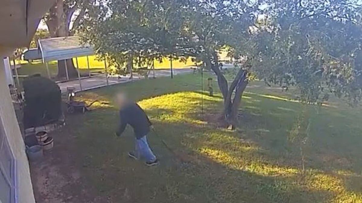 Surveillance video of man carrying shotgun across lawn