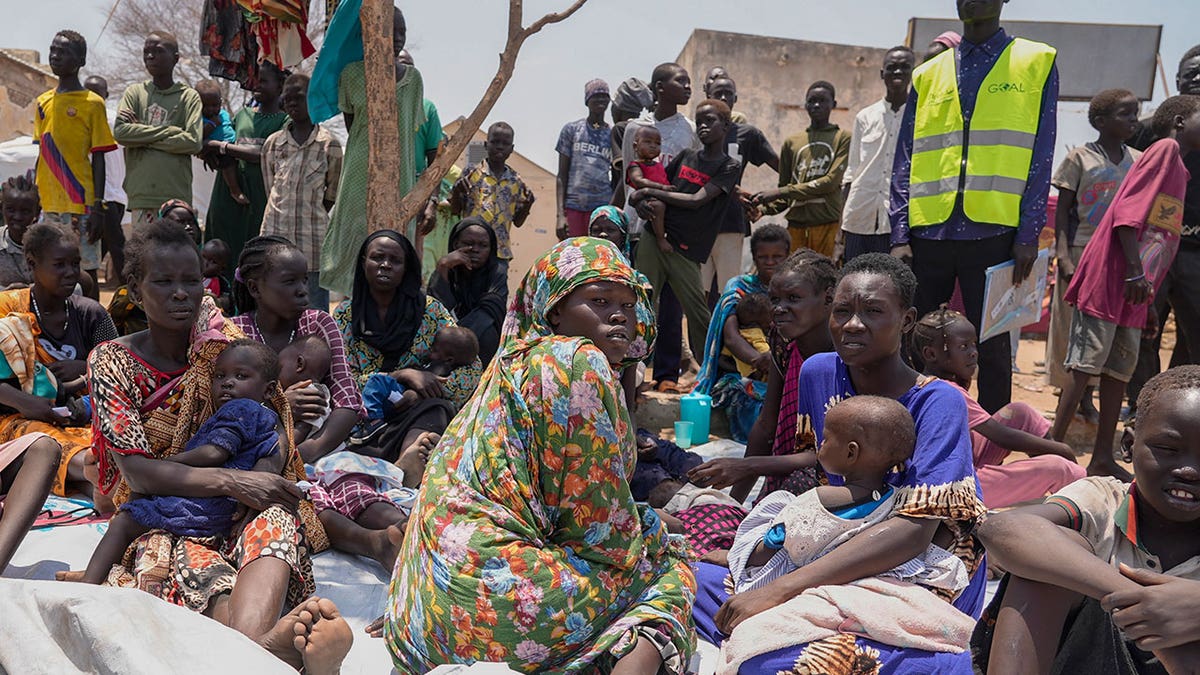 Sudaneses sentam-se em uma clínica com crianças