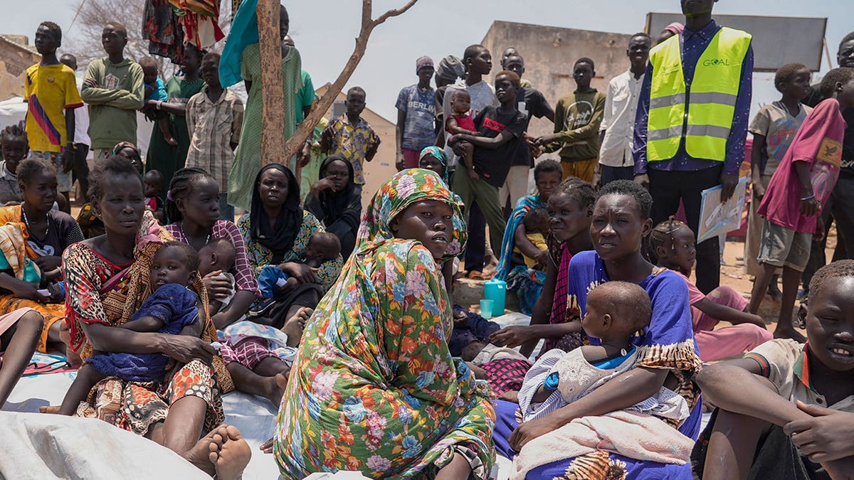 sudanese people sit at a clinic with children