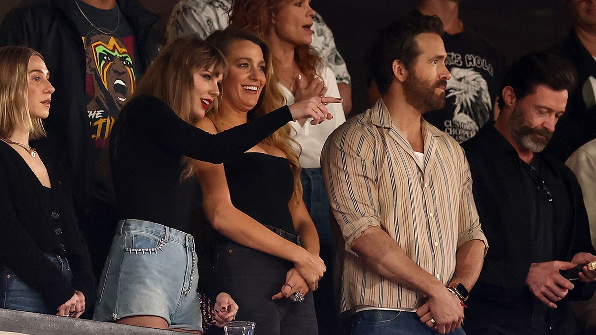 Taylor Swift points at the field next to Blake Lively, Ryan Reynolds and Hugh Jackman