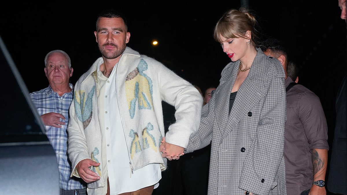 Travis Kelce holds Taylor Swift's hand as he leads her to the car