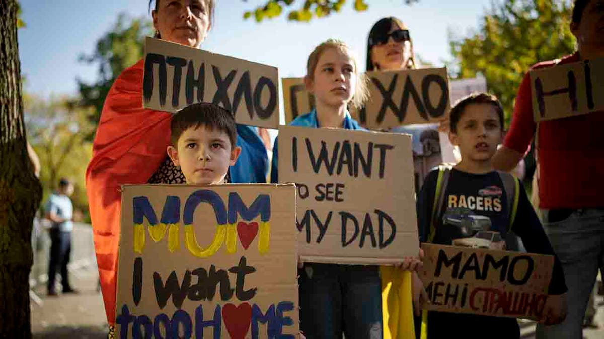 Ukrainian children hold banners