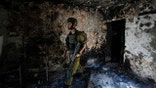 An Israeli soldier inspects a house damaged by Hamas militants in Kibbutz Kfar Azza, Israel