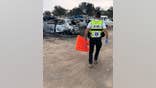 ZAKA volunteer walking with stretcher toward burned down cars