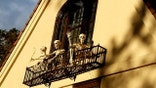 Skeletons waving from a balcony of a home