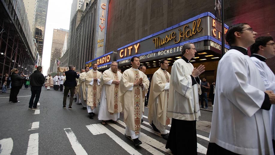 Catholic priests make a procession past Radio City Music Hall