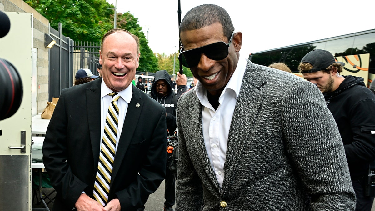 Deion Sanders laughs with the Colorado AD
