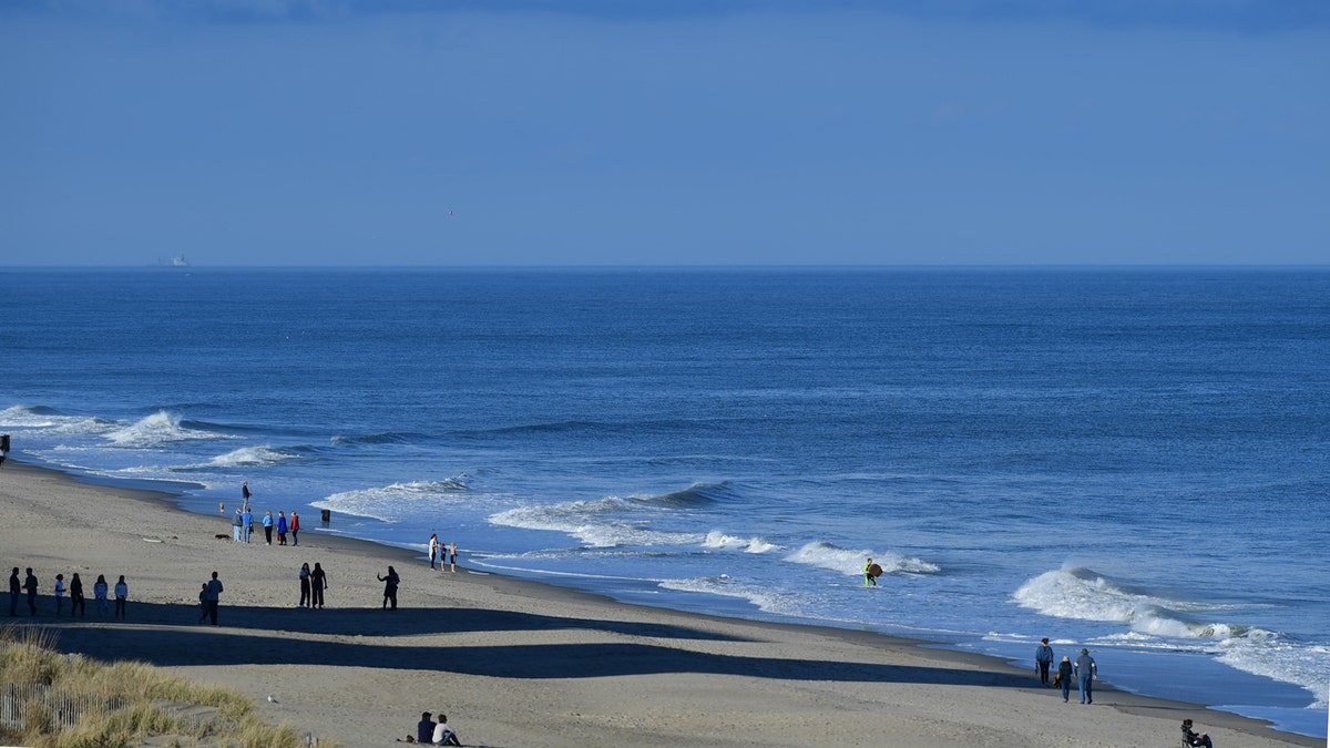 Visitors walking and sitting on Rehoboth Beach shore