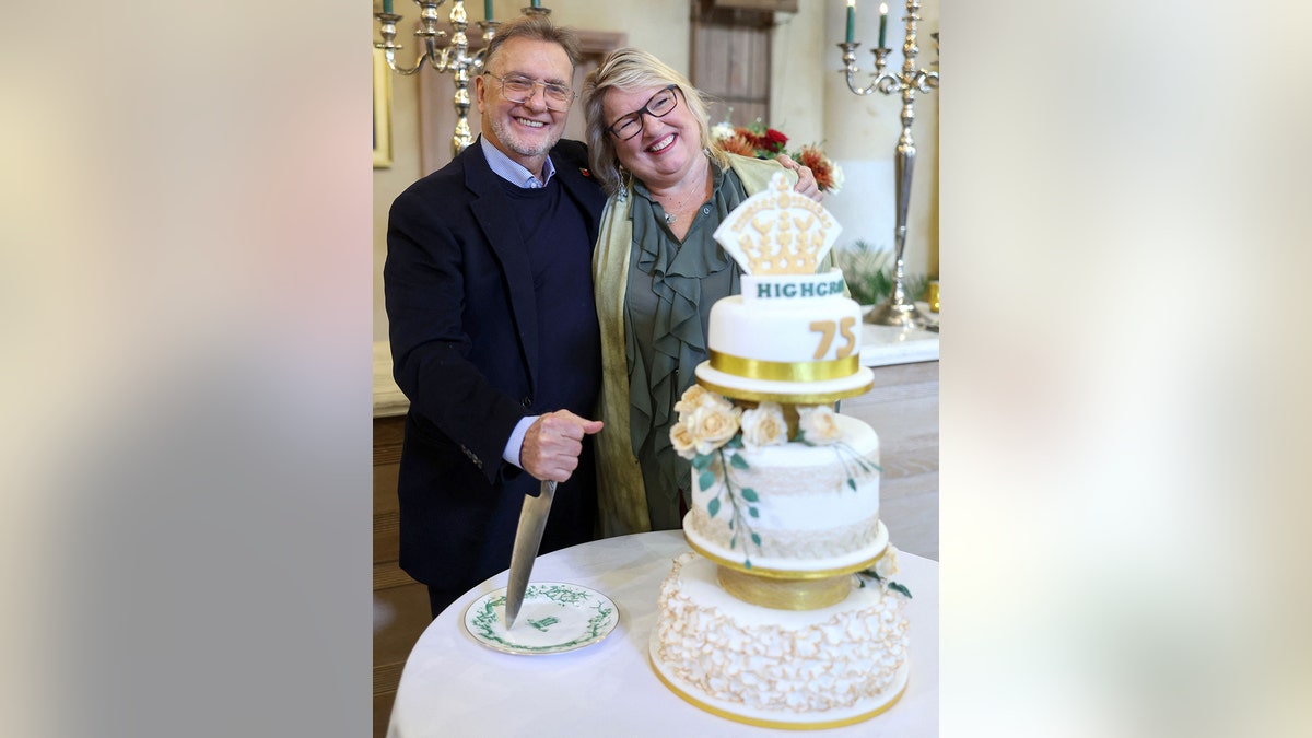 Raymond Blanc e Jan Blackmore sorrindo atrás do bolo de aniversário do rei