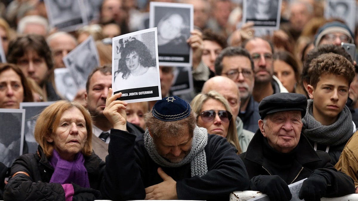 People holds images of those killed in the 1994 bombing of a Jewish community center in Argentina