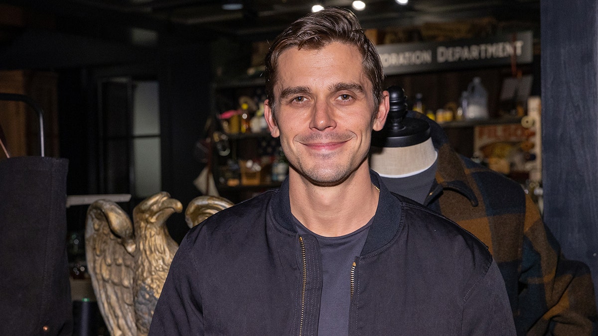 Antoni Porowski sonríe suavemente con chaqueta y camisa azul marino en Seattle