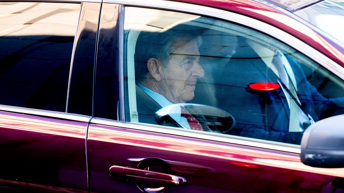 Paul Pelosi sitting in the front seat of a red car outside a San Francisco courthouse