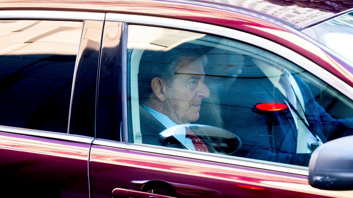 Paul Pelosi sitting in the front seat of a red car outside a San Francisco courthouse