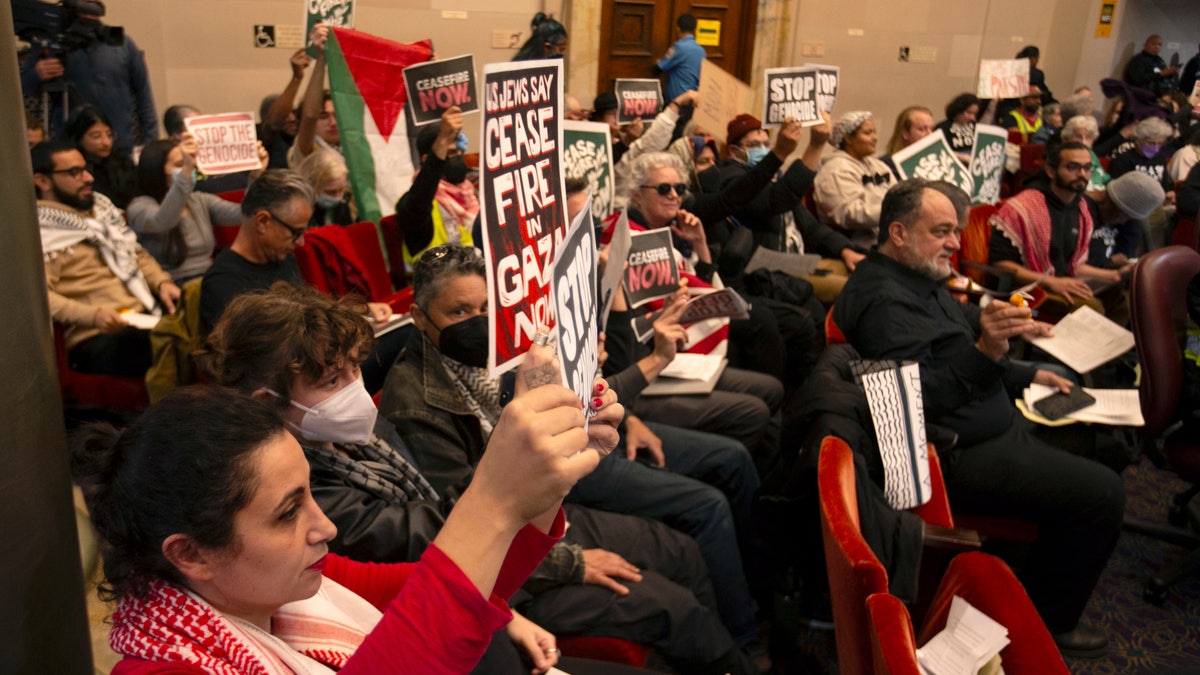 Audience members hold pro-Palestinian signs