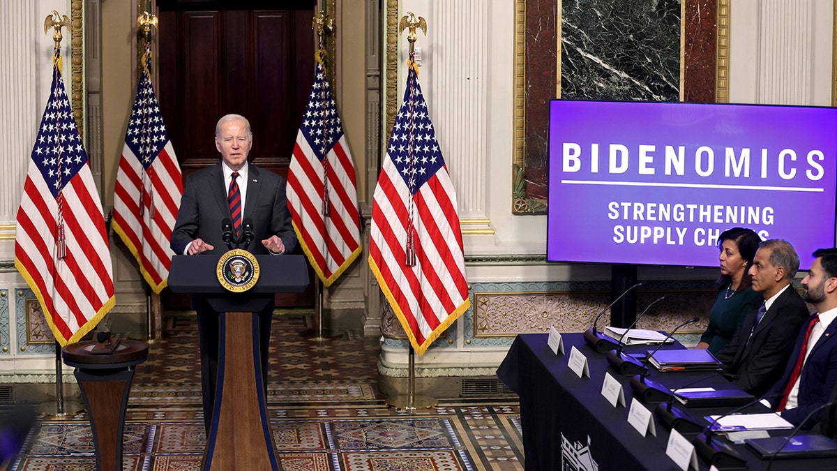 Biden stands next to Bidenomics graphic