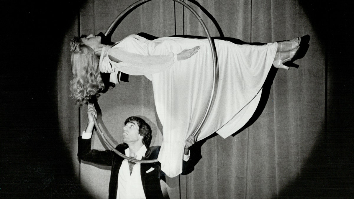 David Copperfield esegue un trucco di levitazione con un'assistente donna