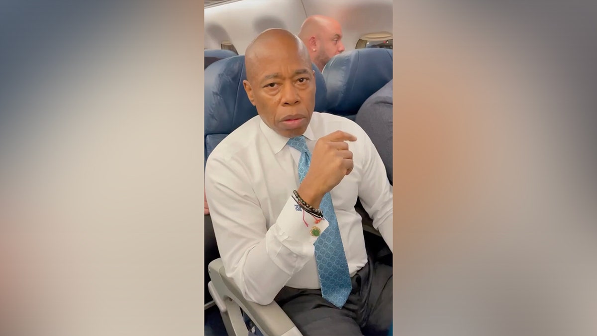 New York Mayor Eric Adams speaking into the camera on a Washington D.C. bound plane Thursday