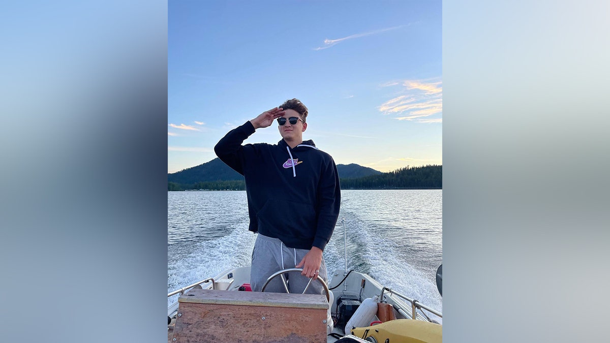 Ethan Chapin salutes at the helm of a classic Boston Whaler boat
