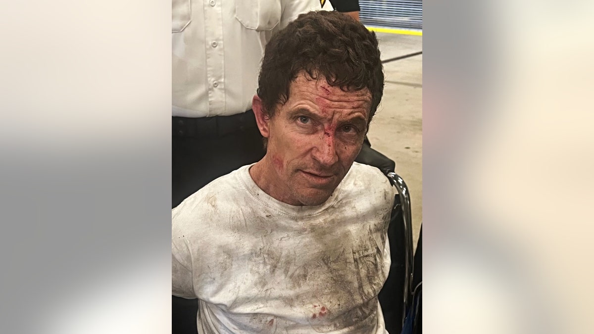 Sean Williams being apprehended after escaping jail with dirt and blood on his t-shirt and face